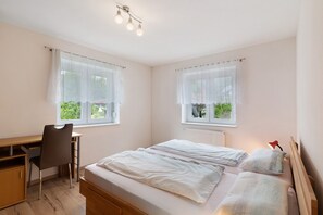 A bedroom with a bed, a desk, and a chair.