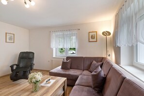 A living room with a leather recliner, a brown sofa, a wooden coffee table, and a vase of flowers.