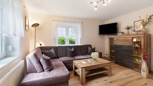 A living room with a sofa, a coffee table, a TV, and a cabinet with shelves. - Apartment "Völker" with Shared Garden & Wi-Fi (Haslach im Kinzigtal)