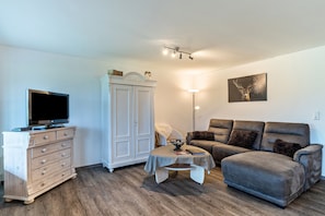 A living room with a television, a cabinet, a sofa, a table, and a wall-mounted artwork. - Apartment 'Eulennest' with Terrace and Wi-Fi (Schramberg)