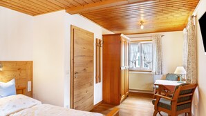 Un dormitorio con techo de madera, cama, escritorio y silla.