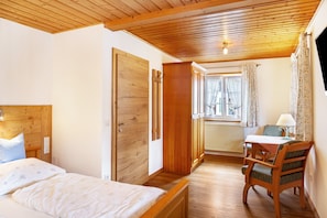 Ein Schlafzimmer mit Holzboden, einem Bett, einem Schreibtisch und einem Stuhl.