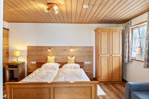 Una stanza con pannelli in legno, un letto, un armadio e un comodino con una lampada.