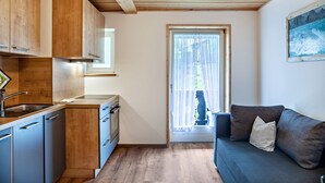 A compact kitchen with wooden cabinets, a built-in oven, and a window with curtains. - Renovared Apartment "Lengdobler - Leni" with Mountain View, Balcony & Wi-Fi (Bad Kohlgrub)