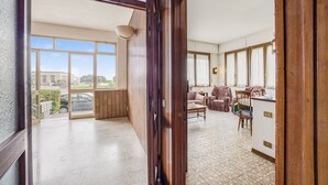 A spacious room with a large window, a wooden door, and a tiled floor. - Annamaria's House Beachfront in Viareggio, Viareggio, Italy (Viareggio)