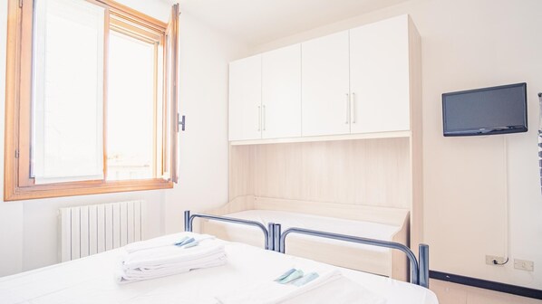 A hospital room with a bed, a window, a TV, and a cabinet.