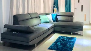 A modern living room with a sectional sofa, teal curtains, and a blue rug. - House near the beach 4B/2Bath (San Juan)