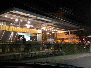 Un restaurant doté d’une terrasse couverte par un auvent et dont la façade est peinte en jaune.