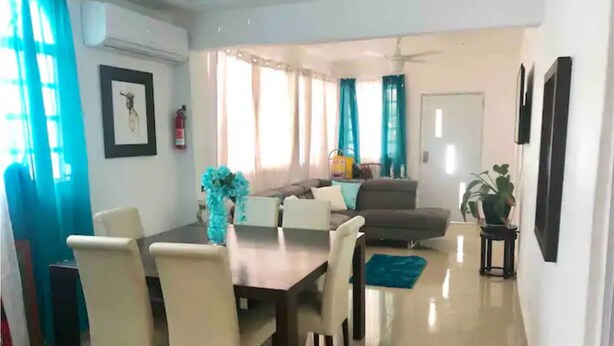 A dining area with a table and chairs, a sofa, and a potted plant. - House near the beach 4B/2Bath (San Juan)