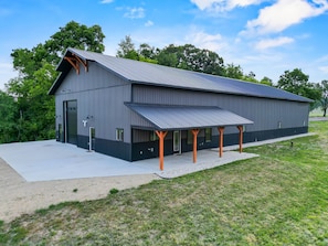 A large industrial-style building with a metal roof and a covered outdoor area supported by orange beams.