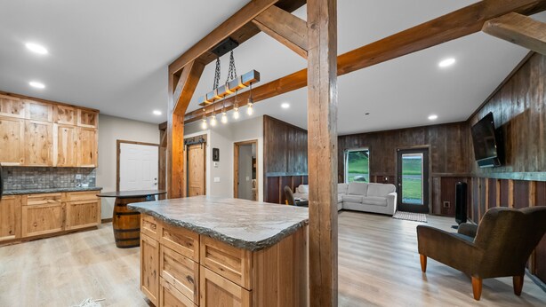 A spacious kitchen with wooden cabinets, a large island, and a dining area with a sofa and chair.