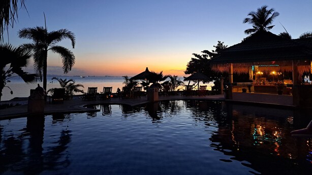A serene pool area with lounge chairs and a bar, overlooking a calm body of water at dusk. - Sense Asia Beach Resort (Ko Pha-ngan)