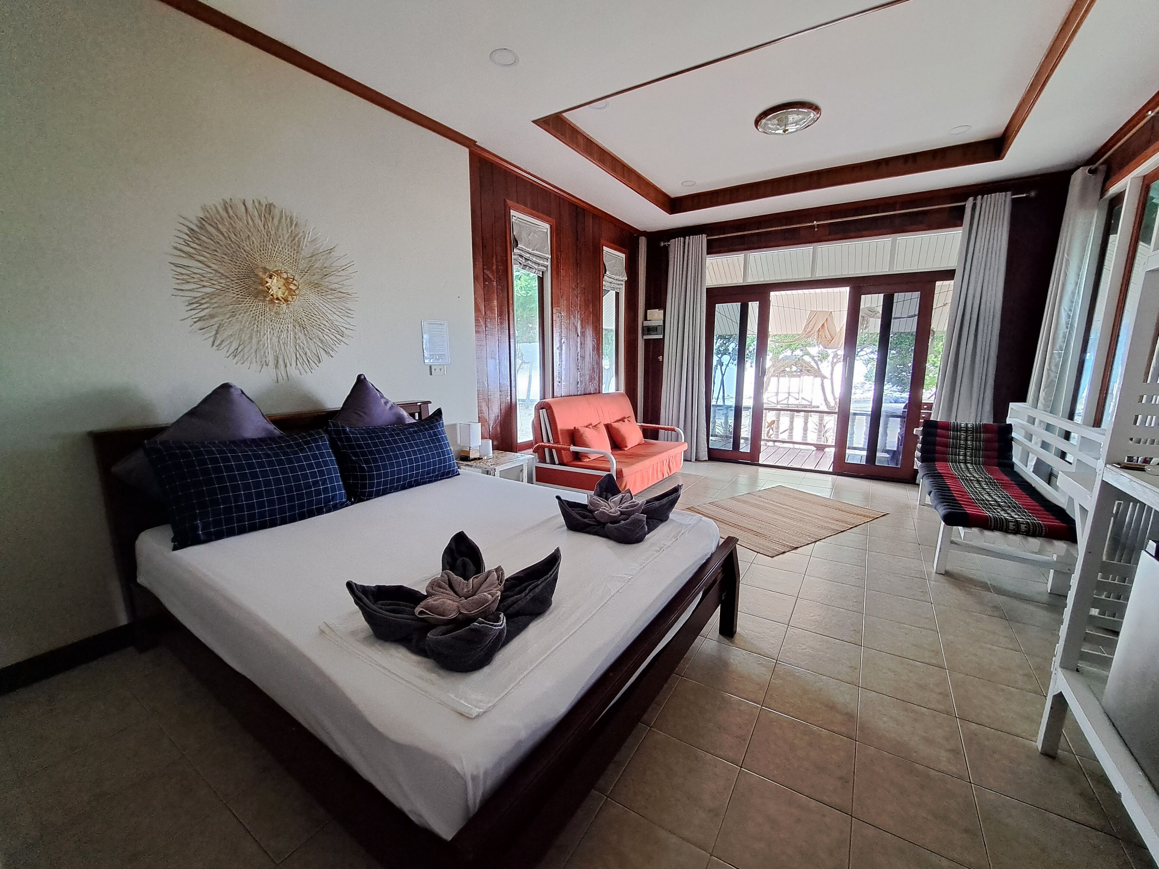 Un dormitorio amplio con una cama grande, una zona de estar con sofá y sillón, y un balcón con vistas.