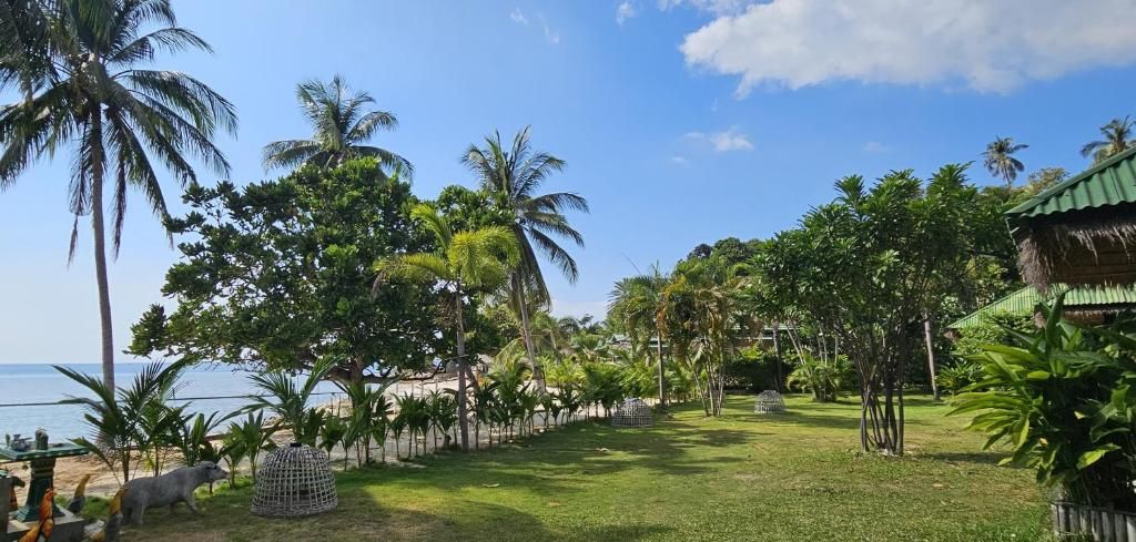 Um jardim tropical com palmeiras e uma construção de colmo.