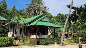 A beachfront bungalow with a green roof, surrounded by palm trees and a clear blue sky. - Sense Asia Beach Resort (Ko Pha-ngan)