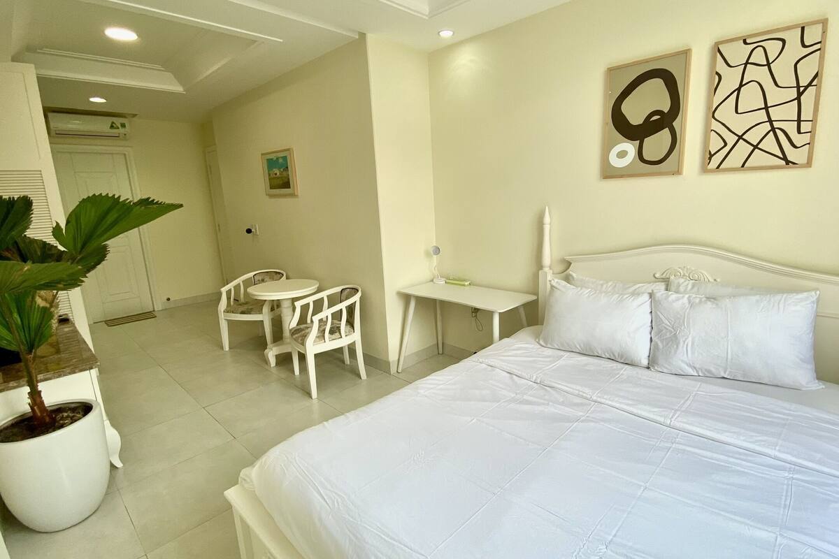 Une chambre d’hôtel avec un lit, un bureau, une chaise et une plante en pot.