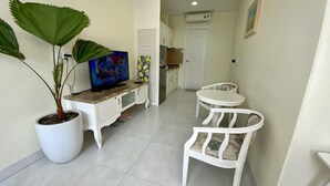 A compact living space with a dining area, a television, and a potted plant.