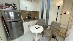 A compact kitchen with a refrigerator, a sink, and a small dining area with a table and chairs.