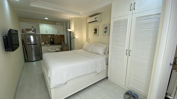 A hotel room with a bed, a wardrobe, a kitchenette, and a bathroom.
