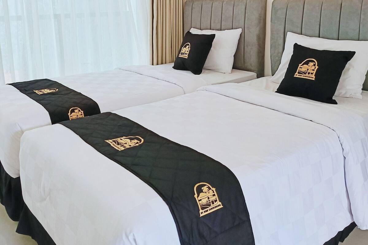 A hotel room with two beds, each with a black and white bedspread and matching pillows.