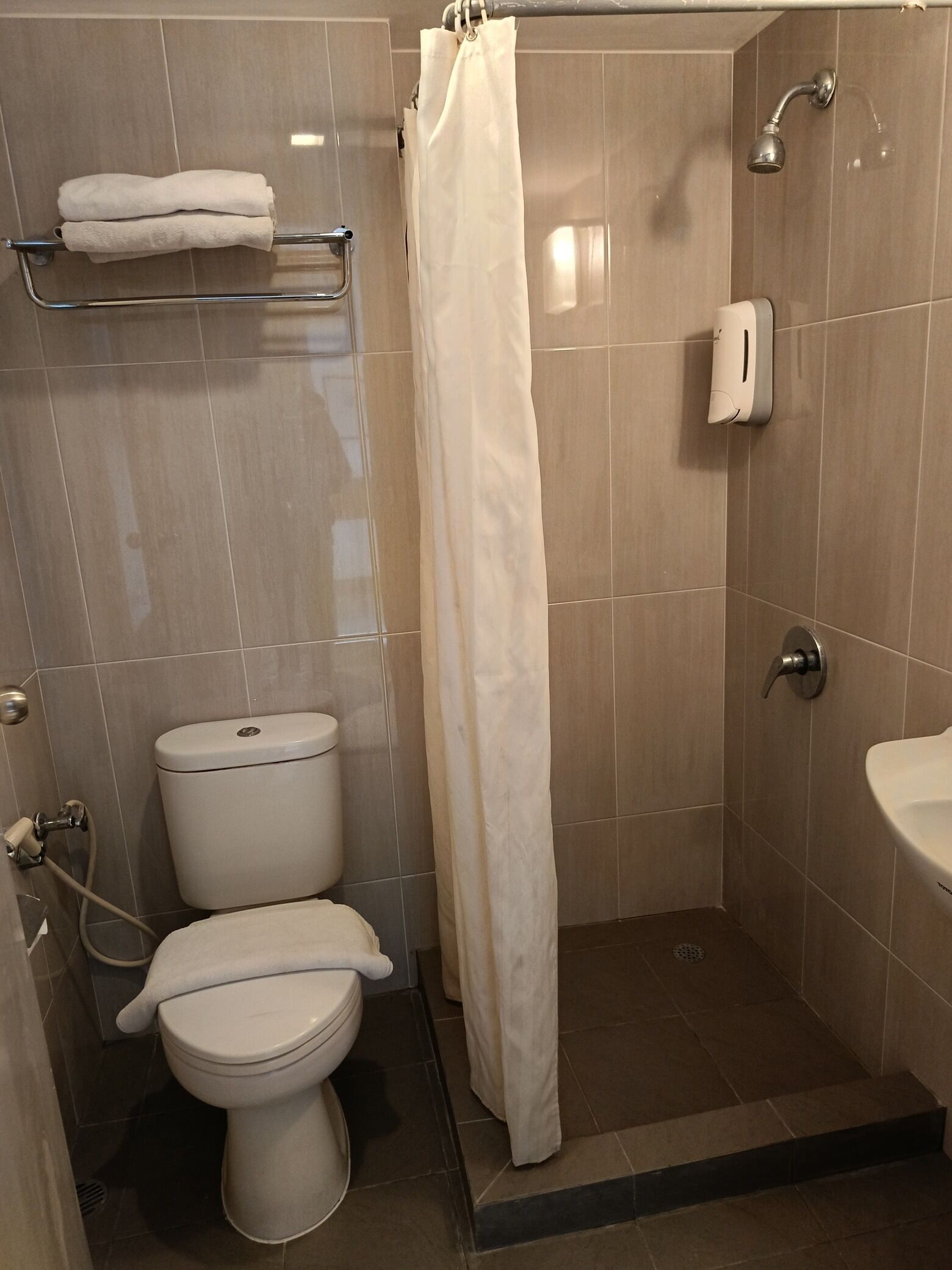 A small, modern bathroom with a toilet, a shower, and a sink.