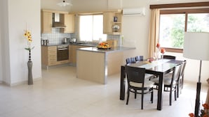 Eine moderne Küche mit einer zentralen Kochinsel, Holzschränken und einem Essbereich mit Tisch und Stühlen.