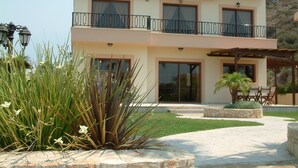 Una casa de dos pisos con balcón, paredes de piedra y un patio con muebles de exterior.