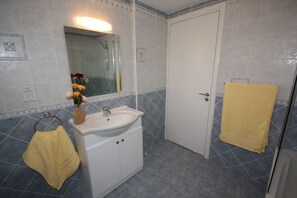 Un bagno con lavandino, specchio e porta asciugamani.