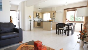 Ein modernes Wohnzimmer mit Sofa, einem Essbereich mit Tisch und Stühlen sowie einer Küche mit Schränken und Geräten.