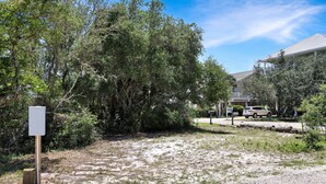 Zona residencial con un campo cubierto de césped, árboles frondosos y una casa con techo inclinado.
