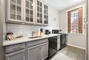 Enjoy cooking in this kitchen with a stainless steel sink, glass-fronted cabinets, and a coffee maker.