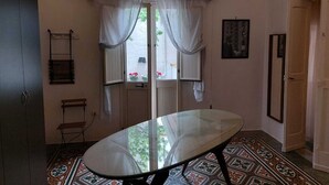 A room with a glass-top table, a patterned floor, a door with a window, and a wall-mounted picture. - Appartamento al mare ad Ugento nel Salento (Ugento)