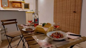 A dining area with a wooden table, chairs, and a bench. There are plates of food, glasses of wine, and a bottle on the table. - Appartamento al mare ad Ugento nel Salento (Ugento)