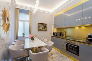 A modern kitchen with a marble countertop, stainless steel appliances, and a dining area with a marble table and upholstered chairs. - Superb Arena View (Pula)