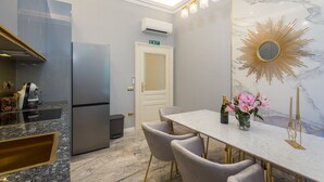 A modern kitchen with a built-in refrigerator, a dining area with a marble countertop, and a decorative mirror. - Superb Arena View (Pula)