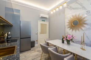 A modern kitchen with a built-in refrigerator, a dining area with a marble countertop, and a decorative mirror. - Superb Arena View (Pula)