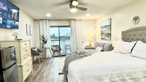 Une chambre d’hôtel avec un grand lit, un bureau avec une chaise, une télévision et un balcon avec vue.