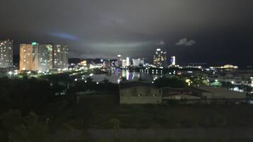 Un paisaje urbano nocturno con edificios iluminados y un cuerpo de agua que refleja luces.