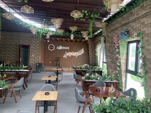 Un café con paredes de ladrillo, mesas de madera y lámparas de mimbre colgantes.