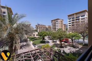 A residential area with multi-story buildings, a playground, and palm trees.