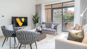 Una sala de estar moderna con un sofá gris, dos sillones, una mesita de centro y un televisor.