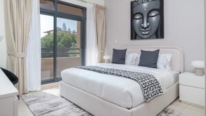 Un dormitorio con cama, escritorio y ventana con cortinas.
