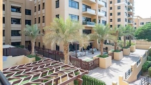 Un edificio residencial de varios pisos con balcones, zonas de estar al aire libre y palmeras.