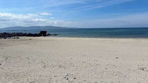 Ein Strand mit felsigem Ufer und blauem Himmel.