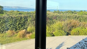 Ein modernes Interieur mit großen Fenstern, die einen Blick auf einen üppigen Garten und ferne Berge bieten.