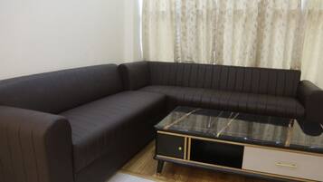 A dark-colored sofa with a glass-top coffee table and a small drawer unit.
