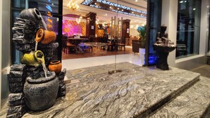 En modern entréhall med en marmordisk i receptionen, en Buddha-staty och en glasfasad som speglar interiören.