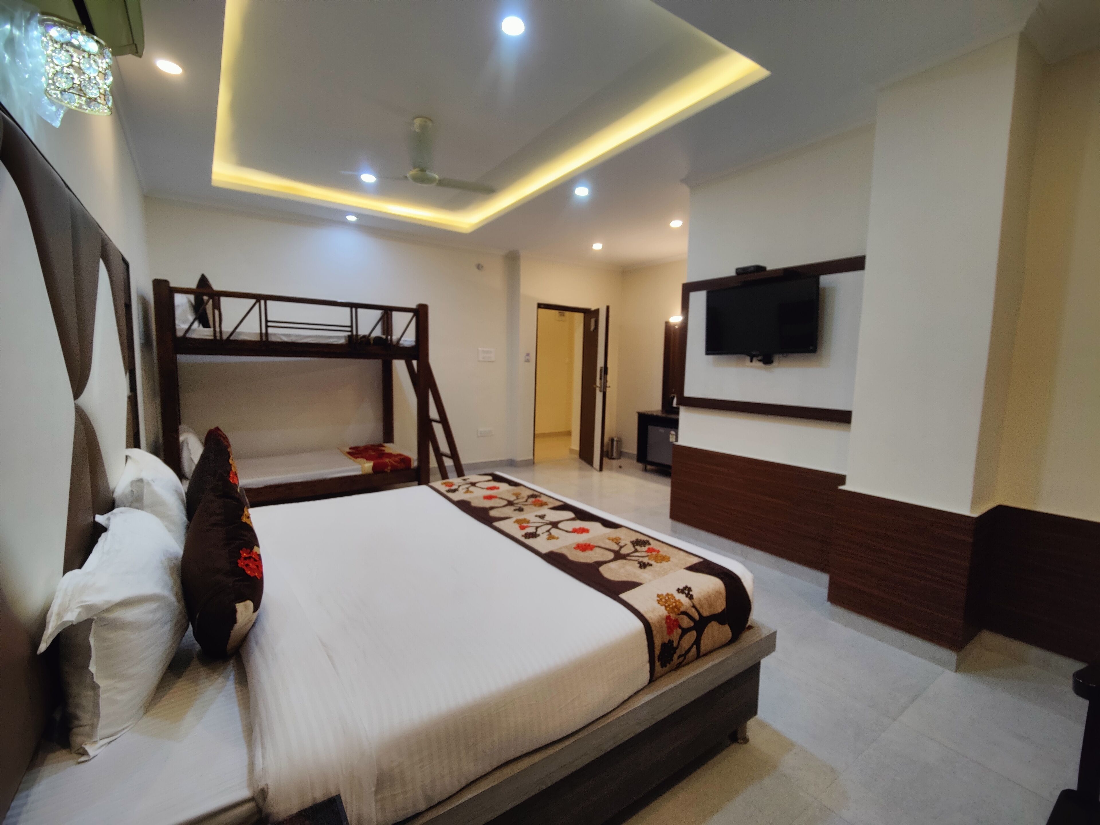 A bedroom with a bunk bed, a flat-screen TV mounted on the wall, and a ceiling fan.