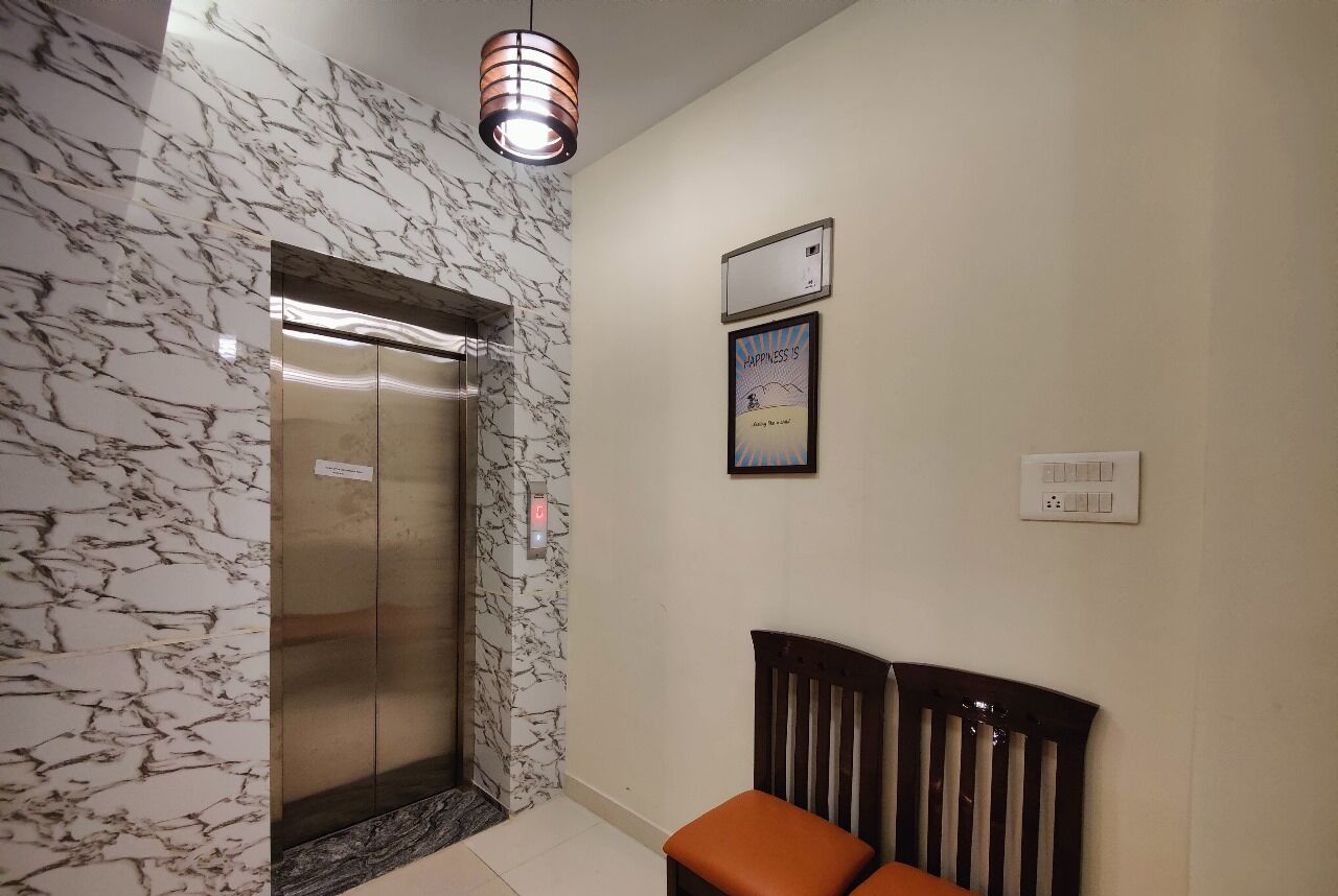 An elevator with a marble wall, a framed poster, and a bench.