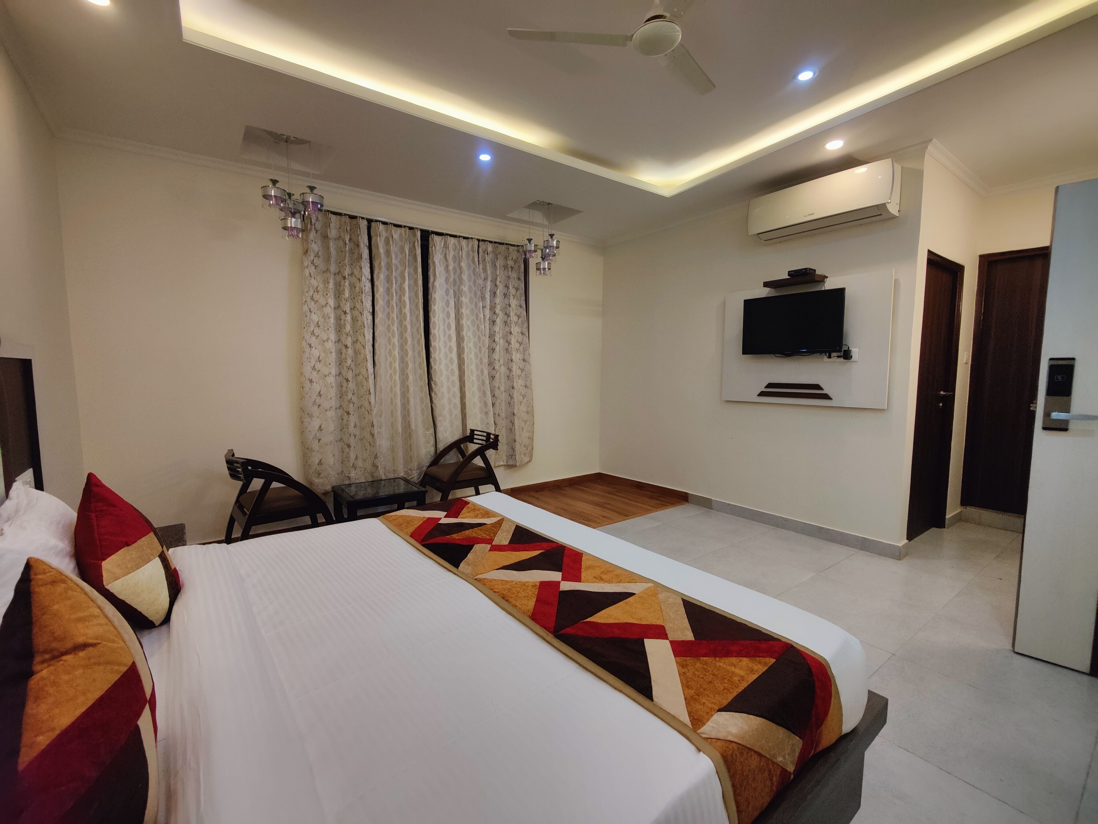 Habitación de hotel con cama, escritorio, silla, televisor montado en la pared y aire acondicionado.